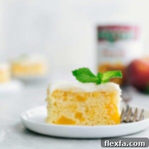 A slice of Peaches and Cream Cake on a plate with cream cheese frosting and visible peach chunks.