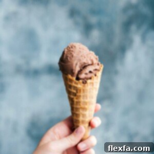 A waffle cone cone filled with rich and creamy homemade chocolate gelato, showcasing its irresistible texture.