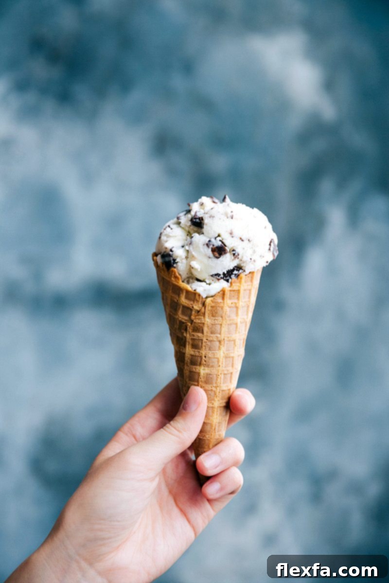 Stracciatella gelato served in a waffle cone, garnished with chocolate shavings, ready to be enjoyed as a refreshing Italian dessert.