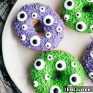 A plate of colorful Monster Halloween Donuts with various sprinkles and candy eyes.