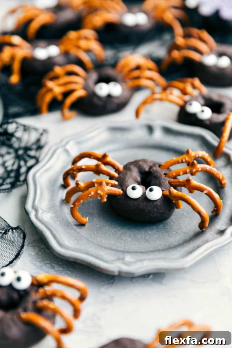Fuzzy and creepy Spider Chocolate Donuts decorated with candy eyes and pretzel legs for a truly arachnid appearance.