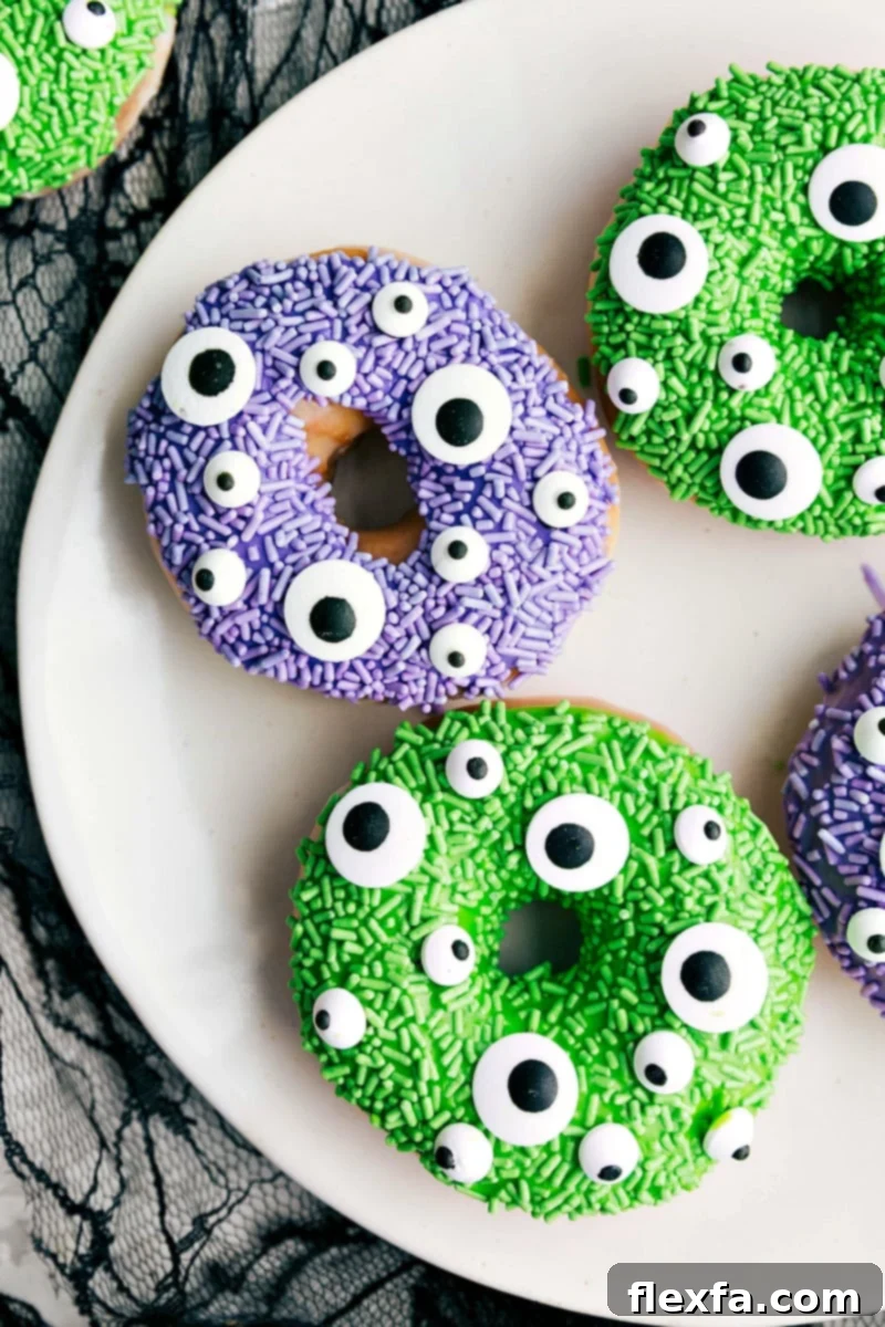 A vibrant plate of Monster Halloween Donuts, bursting with purple and green sprinkles, each featuring whimsical candy eyes.