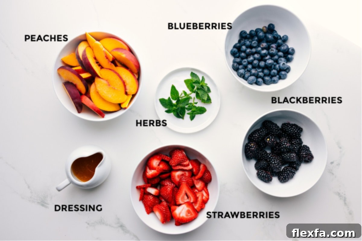 Fresh ingredients laid out for Peach Fruit Salad preparation, including sliced peaches, strawberries, blueberries, blackberries, and fresh mint, alongside citrus for the dressing.