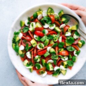 A beautifully presented Caprese Salad with creamy avocado and fresh basil vinaigrette, ready to be served.