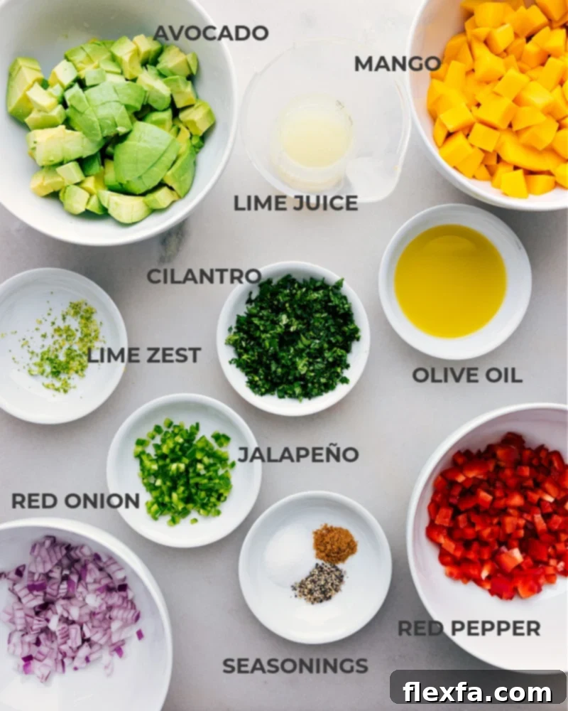 All fresh ingredients for Mango Salsa laid out on a cutting board, including ripe mangoes, avocados, red bell pepper, jalapeño, red onion, cilantro, and limes.