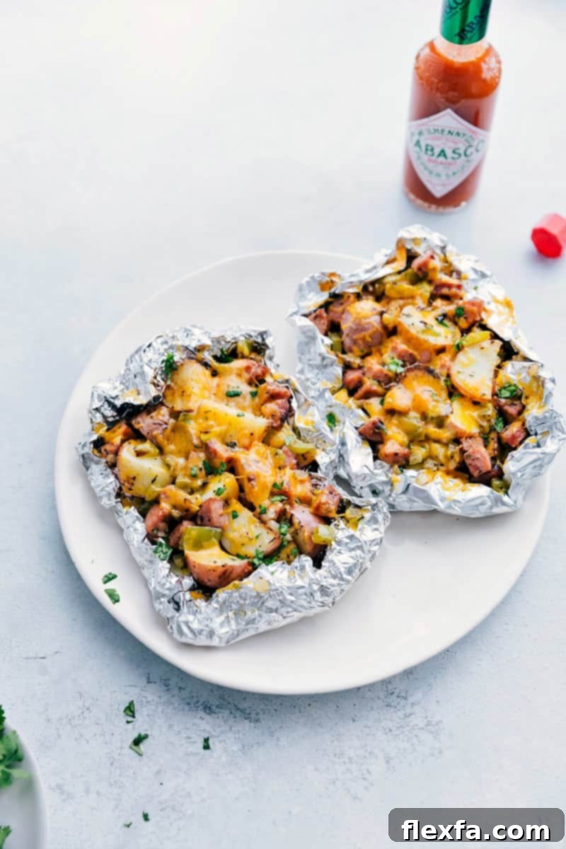 Sausage and Potato Foil Packs fresh off the grill ready to be enjoyed, garnished with fresh cilantro and melted cheese.