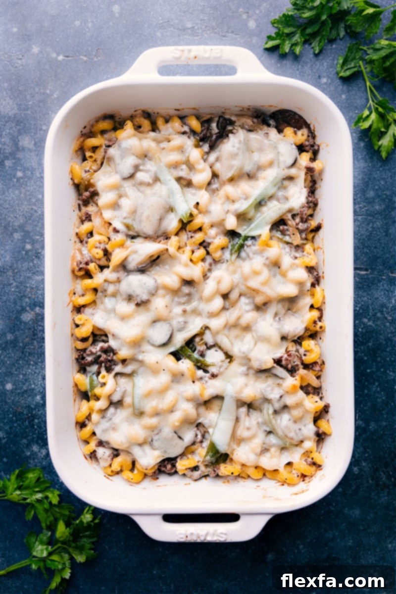 Overhead view of a finished Philly cheesesteak pasta bake in a baking dish, garnished with fresh parsley.