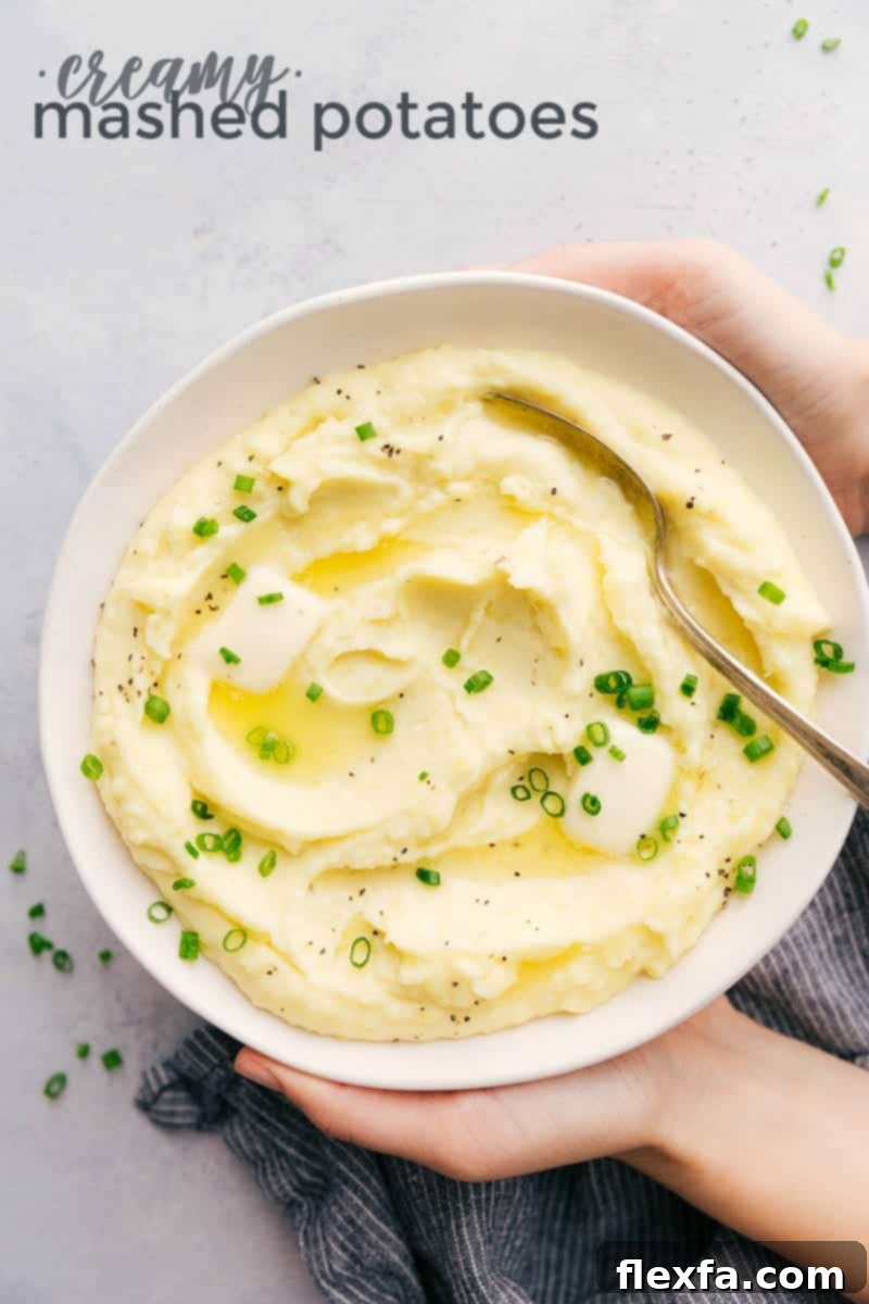 A bowl of rich, creamy mashed potatoes, generously topped with fresh green onions and a dollop of melting butter, ready to serve.