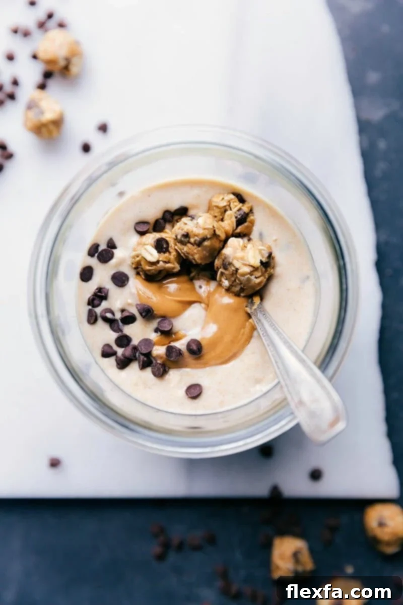 A close-up shot of Peanut Butter Cookie Overnight Oats in a glass jar, featuring a luscious peanut butter swirl and topped with several mini cookie dough balls, ready to be eaten for a healthy breakfast.