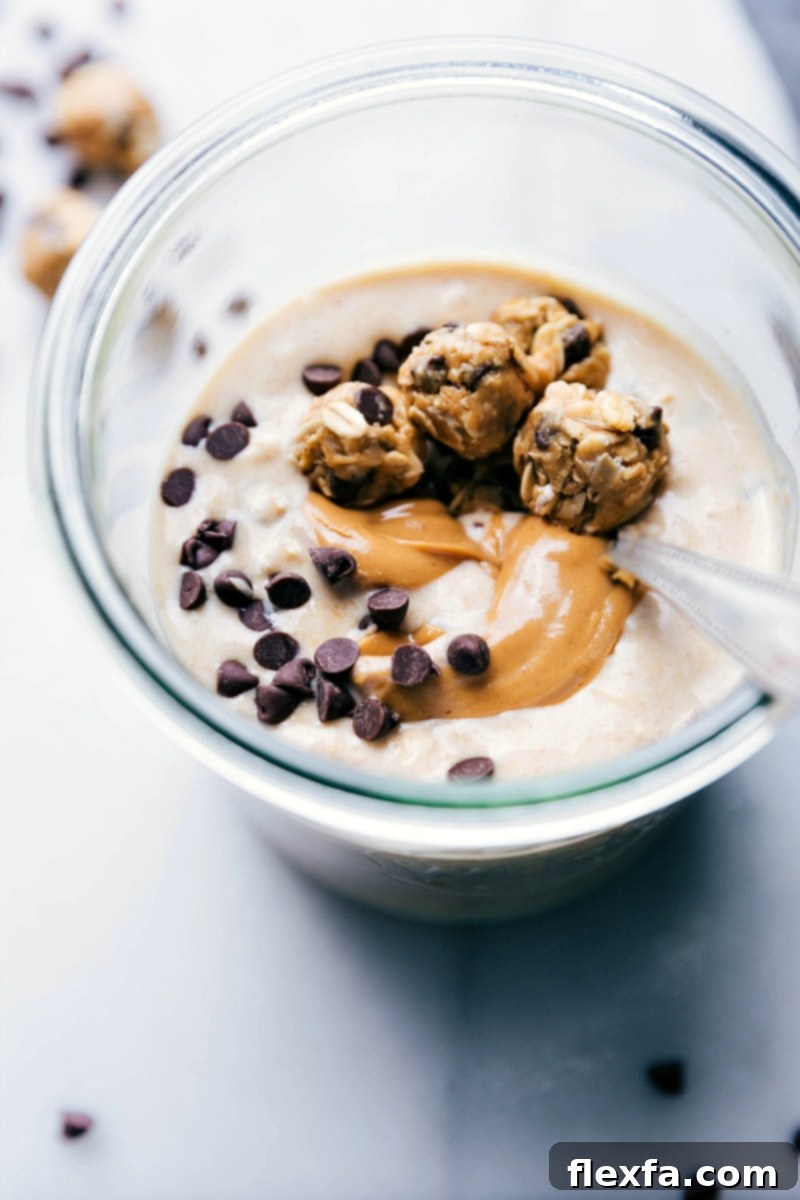 A spoonful of finished Peanut Butter Cookie Overnight Oats being lifted from a glass cup, showing the creamy texture and delicious toppings, including a peanut butter swirl and mini cookies, ready for a healthy breakfast.