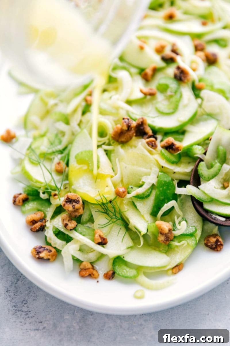 Plated apple fennel salad garnished with walnuts and cheese