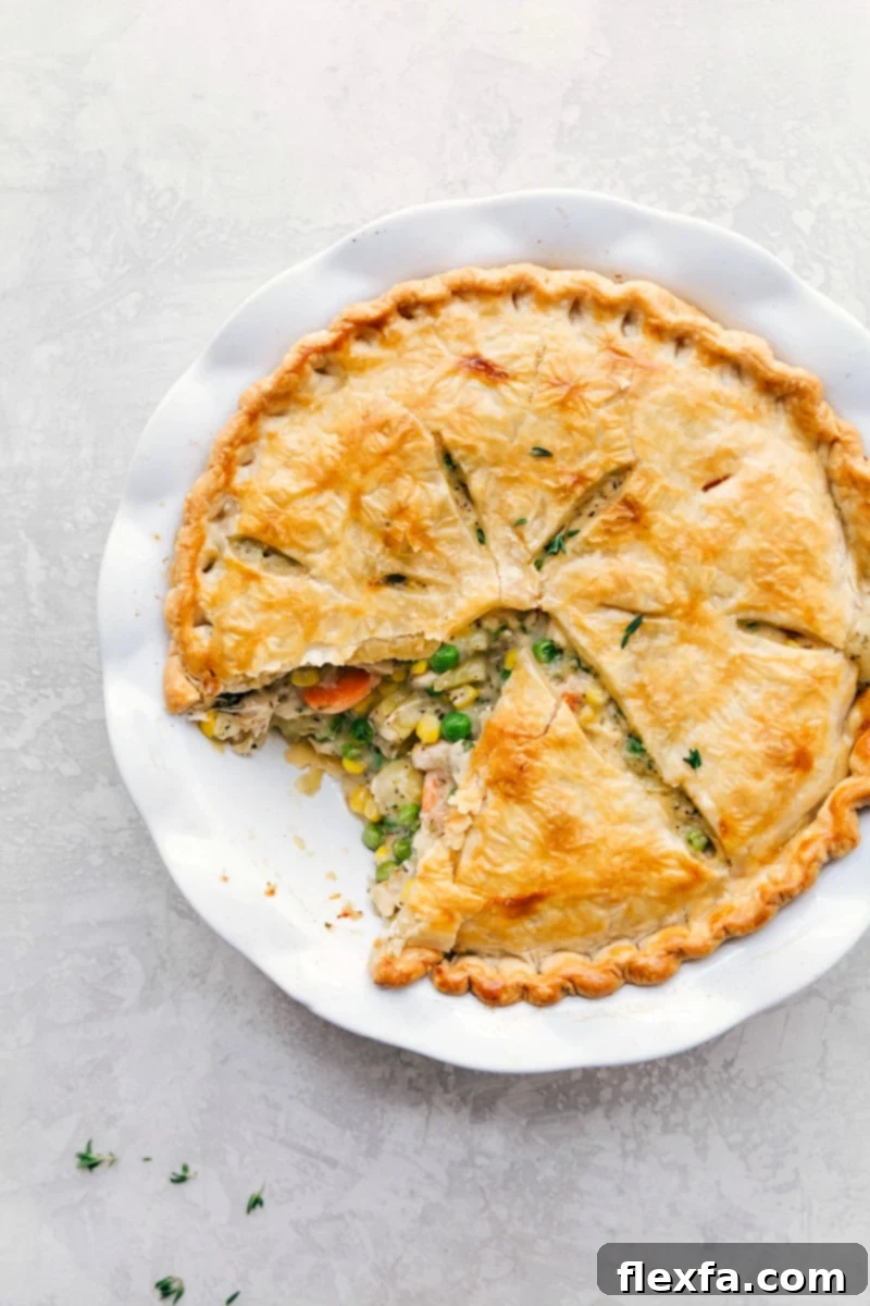 Freshly baked turkey pot pie with a golden, flaky crust, showing a serving already scooped out, revealing the creamy filling.