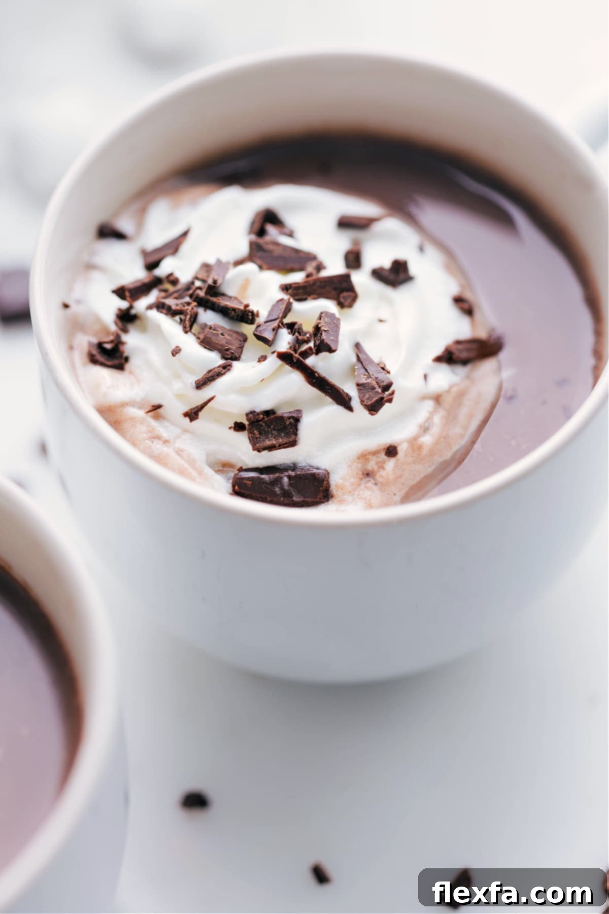 A beautifully presented mug filled with delectable hot chocolate, crowned with a generous dollop of whipped cream and delicate chocolate shavings, promising a moment of pure bliss.