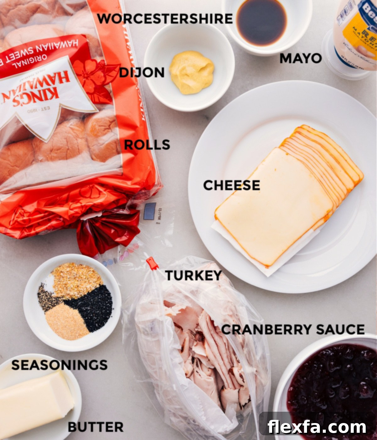 All the ingredients for Turkey Cranberry Sliders prepped for assembly: Hawaiian rolls, Dijon mustard, Worcestershire sauce, mayonnaise, Muenster cheese, cooked turkey, cranberry sauce, and melted butter.