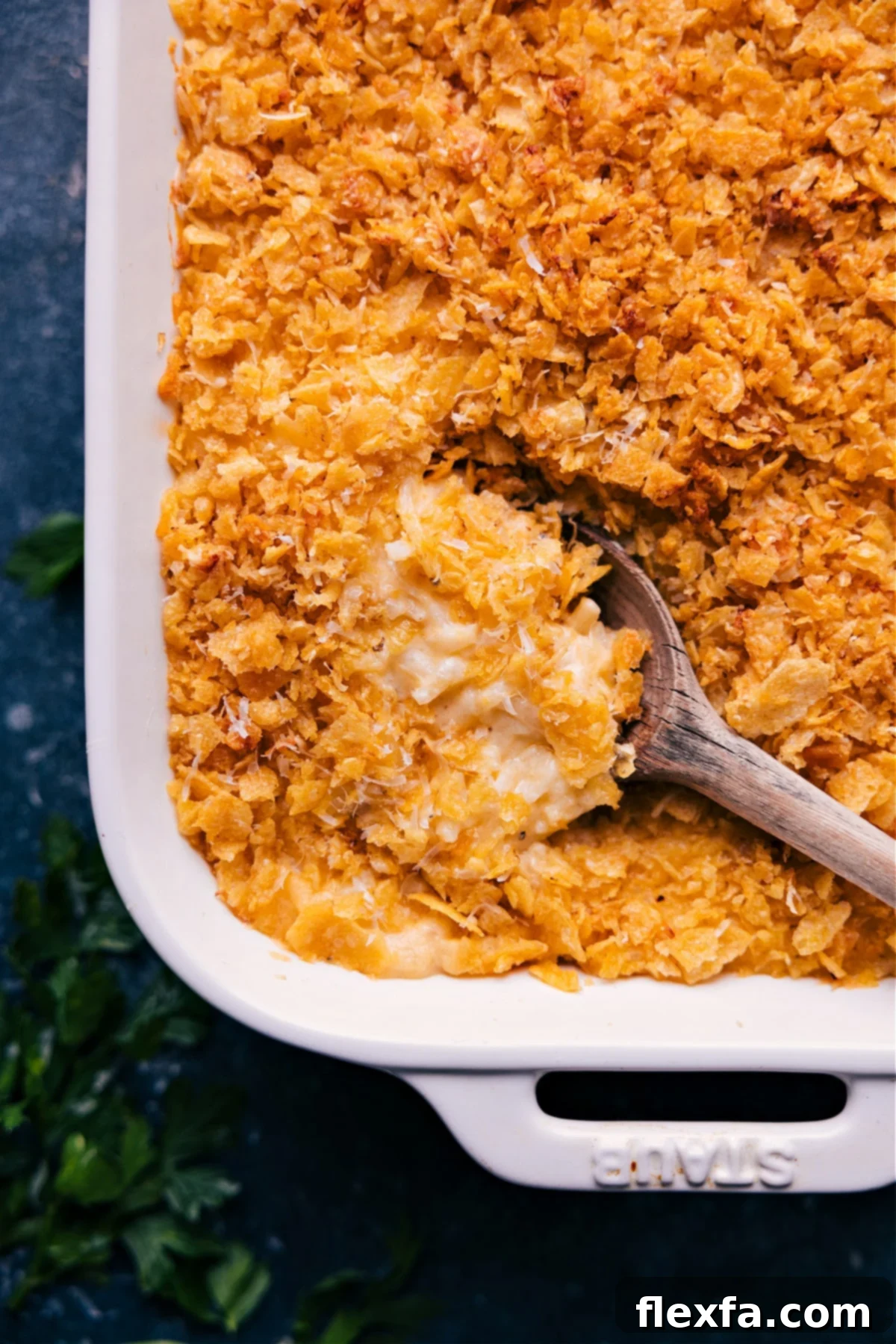 Cheesy And Delicious Funeral Potatoes A generous spoonful of golden-brown Funeral Potatoes, rich with melted cheese and a crispy topping, scooped from a baking dish, highlighting its creamy texture.