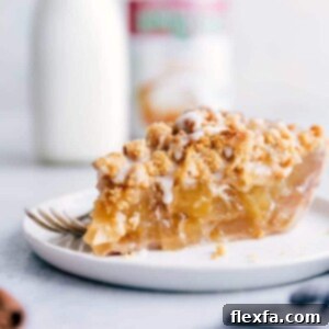 A slice of Cinnamon Roll Apple Pie with icing drizzle