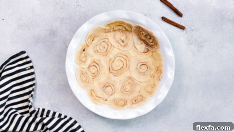 A close-up process image demonstrating how to create the cinnamon roll pie crust, showing sliced pie dough rolled into mini cinnamon buns
