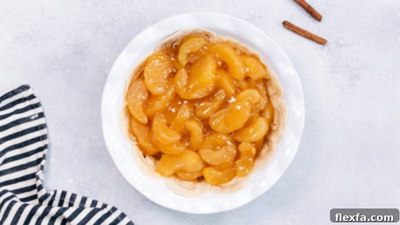Process shot showing a rich apple pie filling being carefully spooned over the unique cinnamon roll pie crust in a pie dish