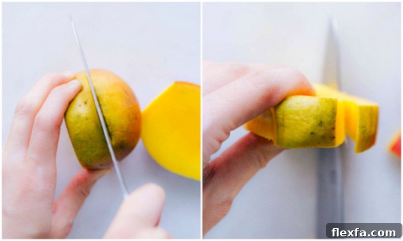 A knife slicing along the side of a mango, carefully avoiding the central pit, to remove one of the large 'cheeks' of fruit.