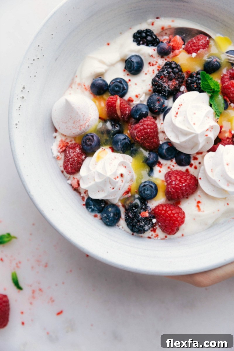 Crisp Meringue Cookies served in a bowl alongside creamy yogurt, fresh berries, and bright lemon curd.
