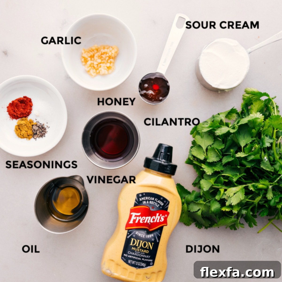 All the dressing ingredients for quinoa black bean salad prepped and ready for easy assembly, including fresh cilantro, minced garlic, sour cream, honey, red wine vinegar, Dijon mustard, and seasonings.