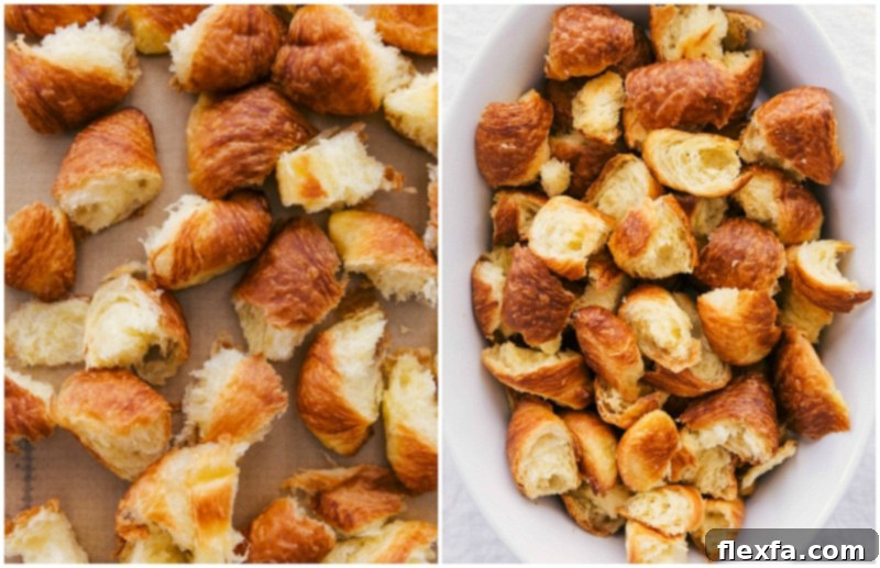 Expertly chopped buttery croissant pieces, torn into perfect 1-inch chunks, ready for drying and soaking in a rich custard. The pieces are evenly spread on a baking sheet, awaiting preparation for a decadent breakfast bake.