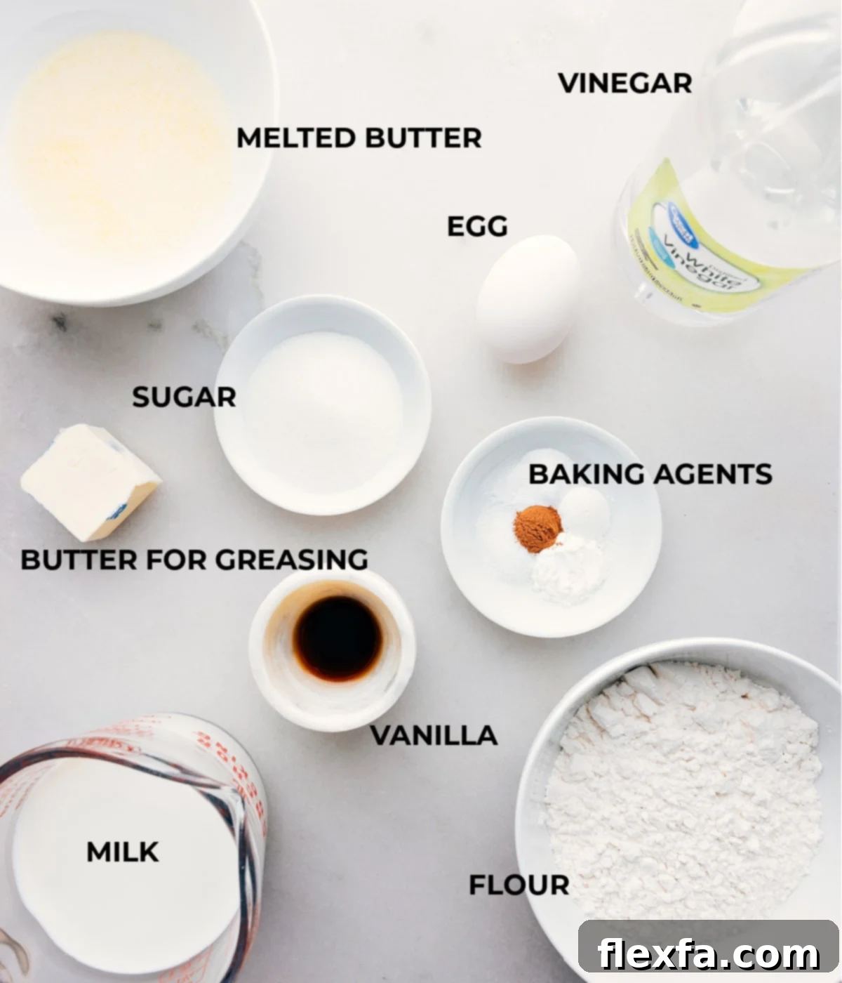 A collection of fresh ingredients laid out, including flour, milk, eggs, butter, sugar, and leavening agents, showcasing all that is needed for these homemade old-fashioned pancakes.