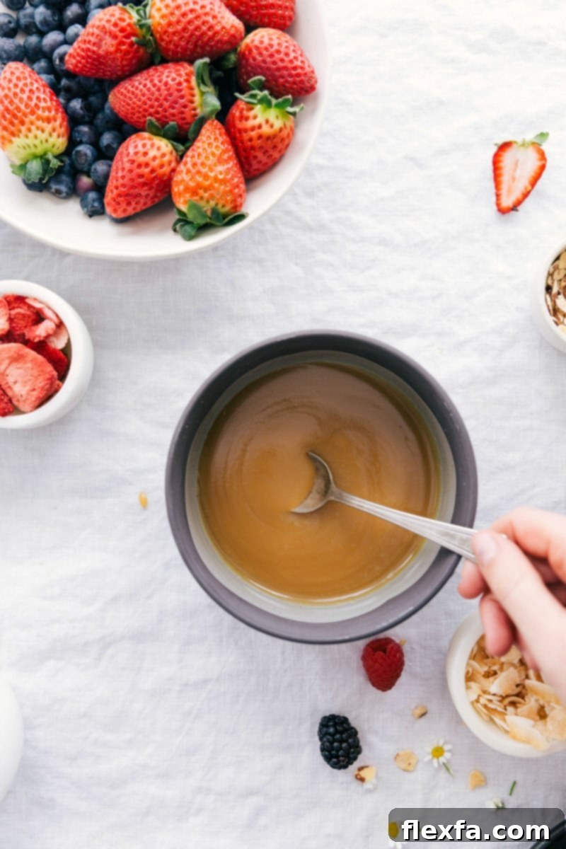 Overhead photo of rich, creamy vanilla sauce in a elegant bowl, surrounded by fresh, vibrant berries