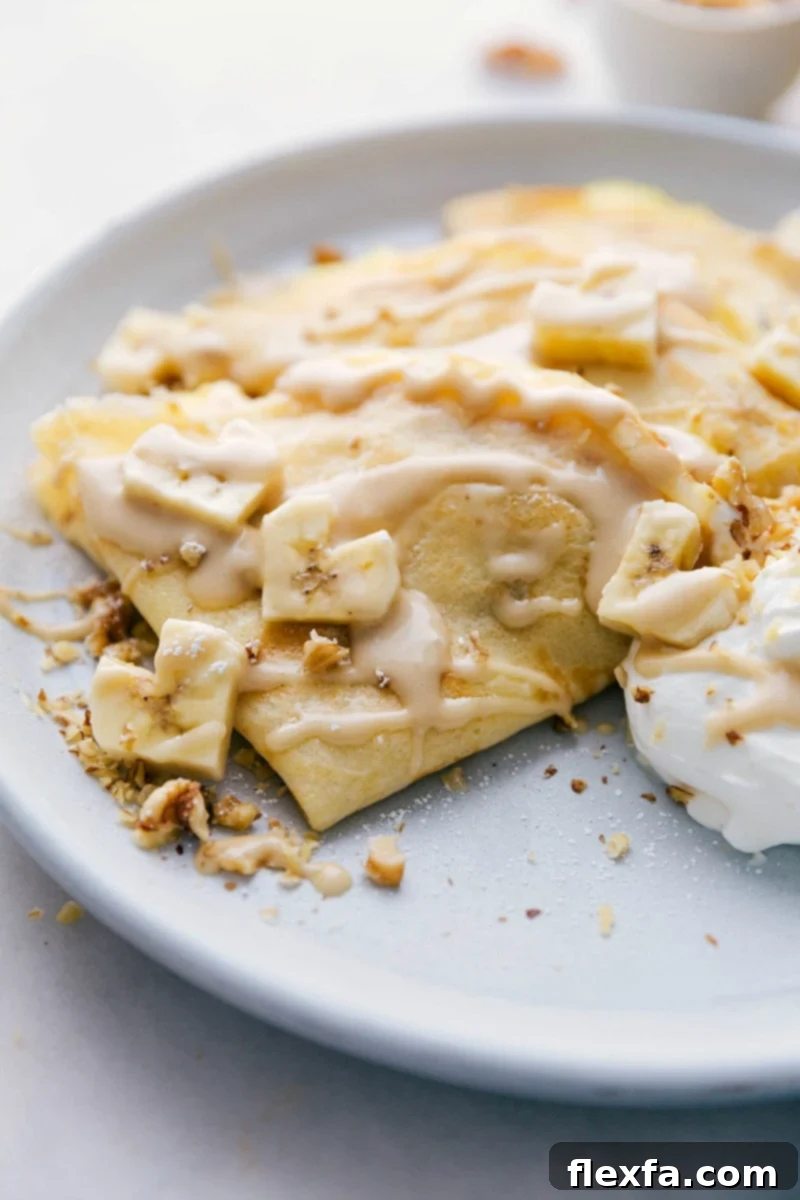 Overhead shot of a plate of beautifully presented Banana Crepes, garnished with fresh banana slices and chopped walnuts, ready to be enjoyed.