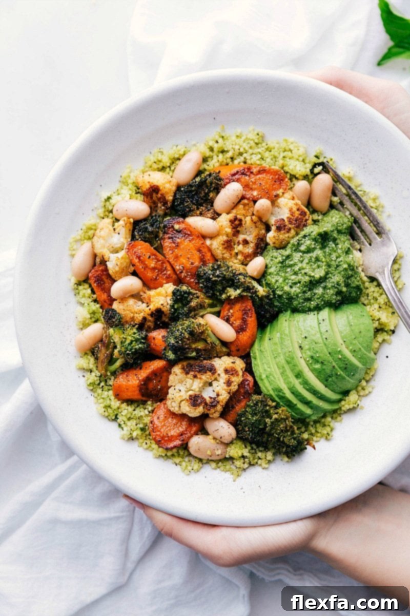 A vibrant and perfectly roasted medley of cauliflower, broccoli, carrots, and white beans beautifully arranged atop a bed of easy 5-minute pesto couscous. This vegetarian Pesto Vegetable Bowl is brimming with flavor, essential protein, and beneficial healthy fats, making it a complete and nourishing meal. Overhead image of the ready-to-eat Pesto Roasted Veggie Bowls, showcasing perfectly roasted vegetables and fluffy couscous.