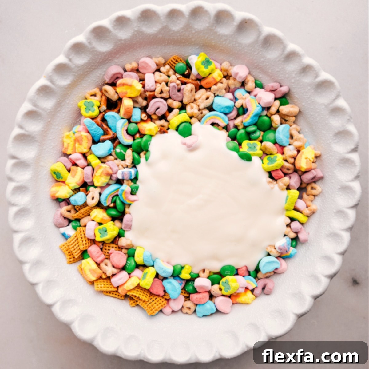 White chocolate is poured into the Leprechaun Bait and ready to mix, transforming the dry ingredients into a cohesive, delicious treat.