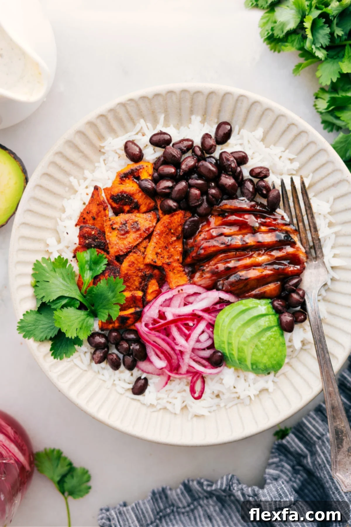 The Best Homemade Sweetgreen BBQ Chicken Bowl Recipe A vibrant BBQ Chicken Bowl featuring rice, perfectly cooked BBQ chicken, sweet potato chunks, black beans, red pickled onions, and sliced avocado, drizzled with creamy green goddess dressing.