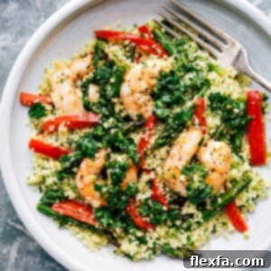 A vibrant bowl of Shrimp Couscous with roasted asparagus and red pepper, topped with a green herb sauce.