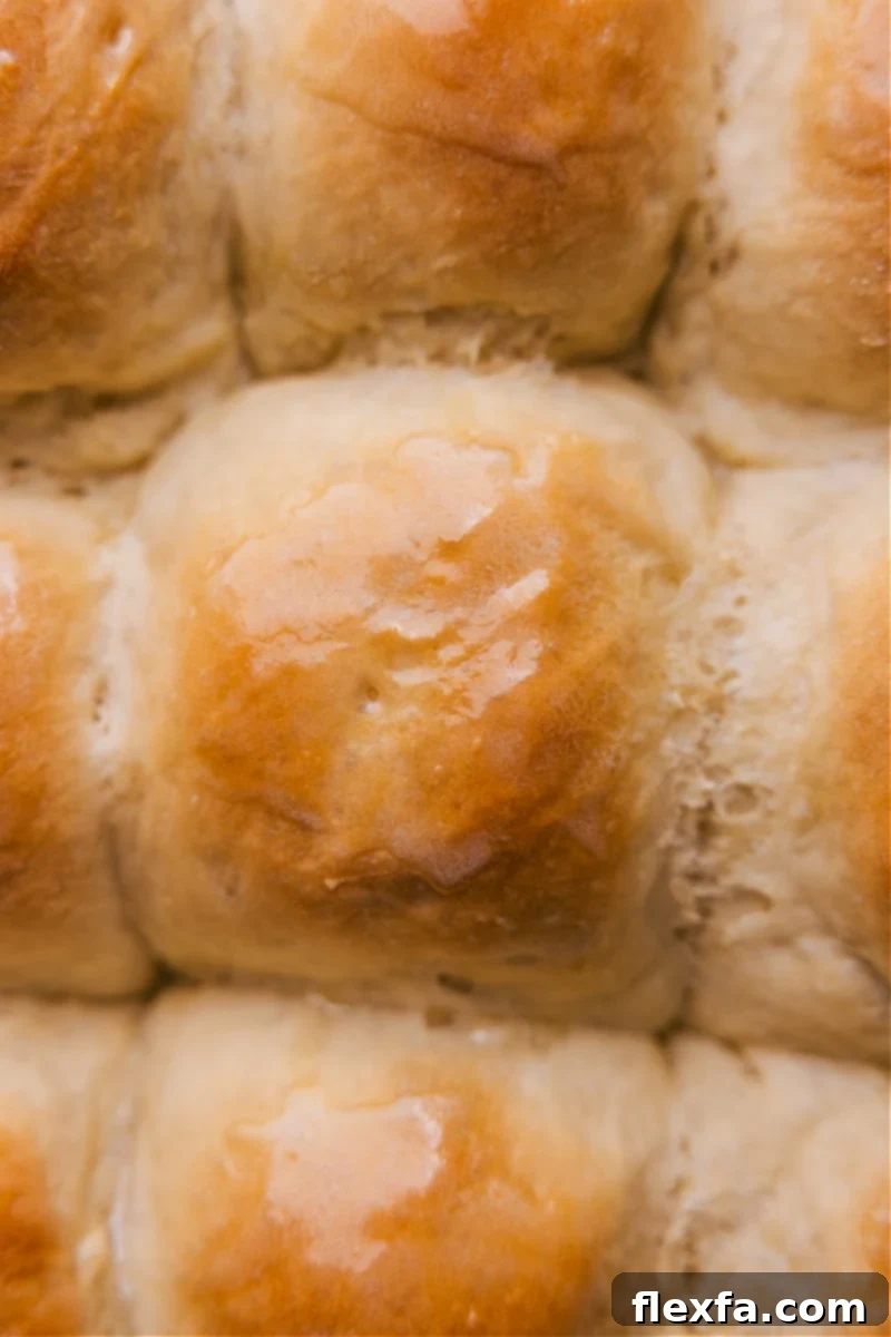 Close-up, overhead view of the finished Life-Changing No-Knead Dinner Rolls, golden brown and glistening with butter, showcasing their irresistible texture.