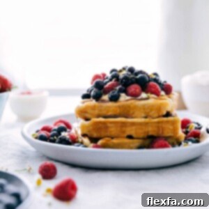 A beautifully presented stack of golden waffles topped with fresh berries and whipped cream, ready to serve.