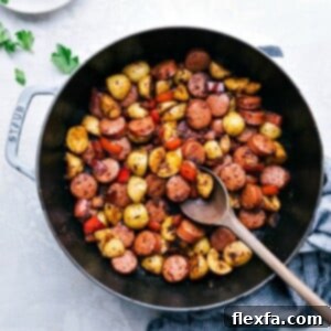 A beautifully presented Sausage and Potatoes Skillet meal, garnished with fresh herbs, in a rustic cast iron pan.