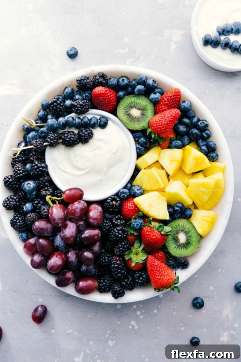 A vibrant platter featuring the ready-to-eat Fruit Dip in a bowl, surrounded by an assortment of colorful fresh fruits like strawberries, blueberries, grapes, kiwi, and pineapple chunks, ready for dipping.
