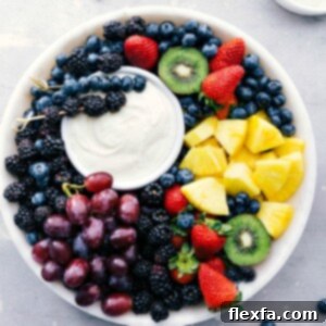 A smaller image of the fruit dip in a white bowl with a variety of colorful fresh fruits arranged around it on a wooden board.