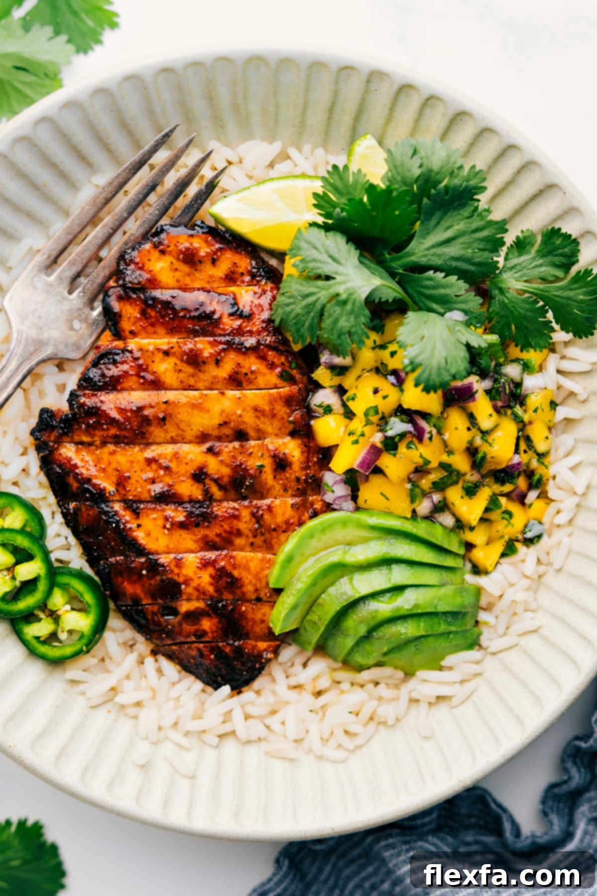 The Perfect Summer Dinner: Mango Chicken with Fresh Mango Salsa Grilled Mango Chicken on a bed of fluffy rice, generously served with a colorful mango salsa and garnished with fresh cilantro.