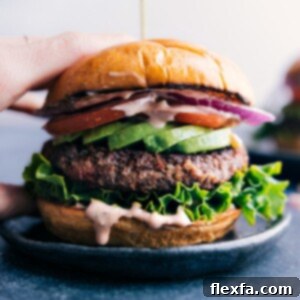 Gorgeous finished black bean burger with fresh vegetables sandwiched between a beautiful buttered bun.