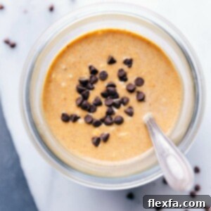 A top-down view of pumpkin overnight oats garnished with chocolate chips in a clear jar, ready to eat.