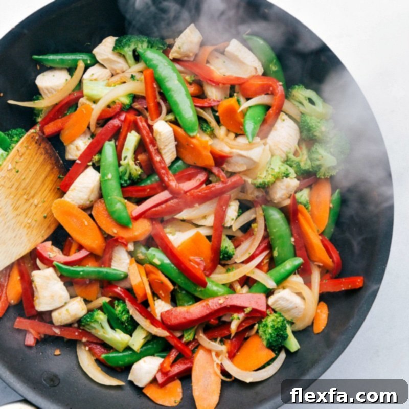Mixing fresh vegetables and meat in the skillet.