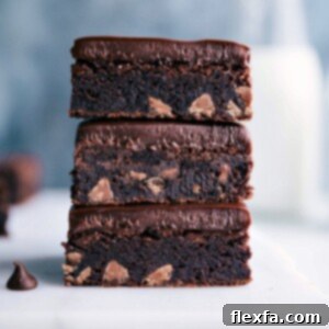 Three gluten-free brownies stacked on top of each other, displaying a fudgy, rich interior packed with gooey chocolate chips, ready to be enjoyed.