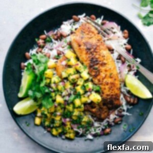 A plate featuring blackened tilapia served with pineapple salsa, rice, and black beans, presenting a flavor-packed and delicious meal.