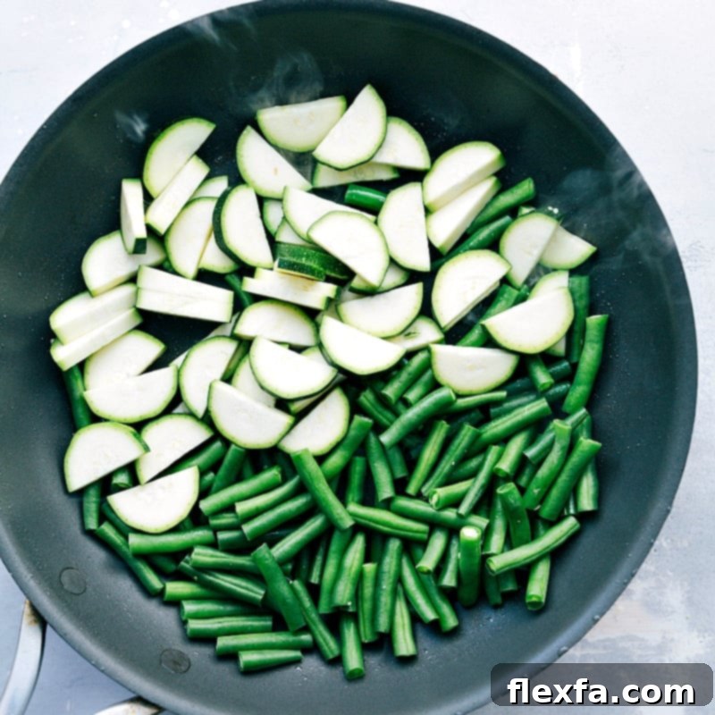Uncooked zucchini and green beans in a skillet, ready for sautéing.