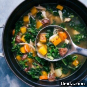 Chicken vegetable soup in the pot, with a ladle scooping up a steaming portion.