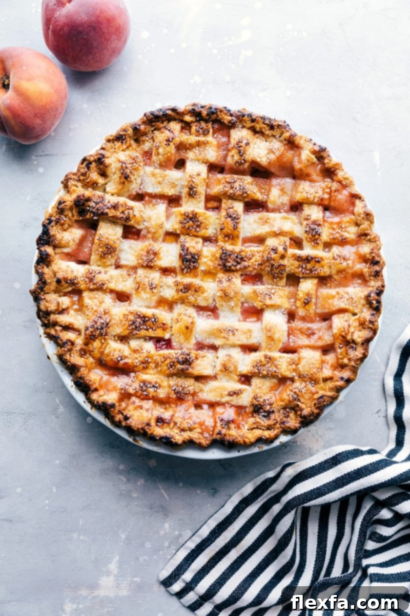 Delicious and sweet peach pie, fresh out of the oven and topped with sugar, accompanied by fresh peaches on the side.