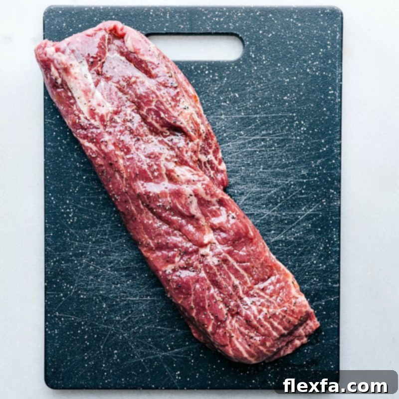 Seasoning Raw Meat for Grilling Raw flat iron steak arranged on a cutting board, ready to be seasoned generously with salt and pepper before grilling.