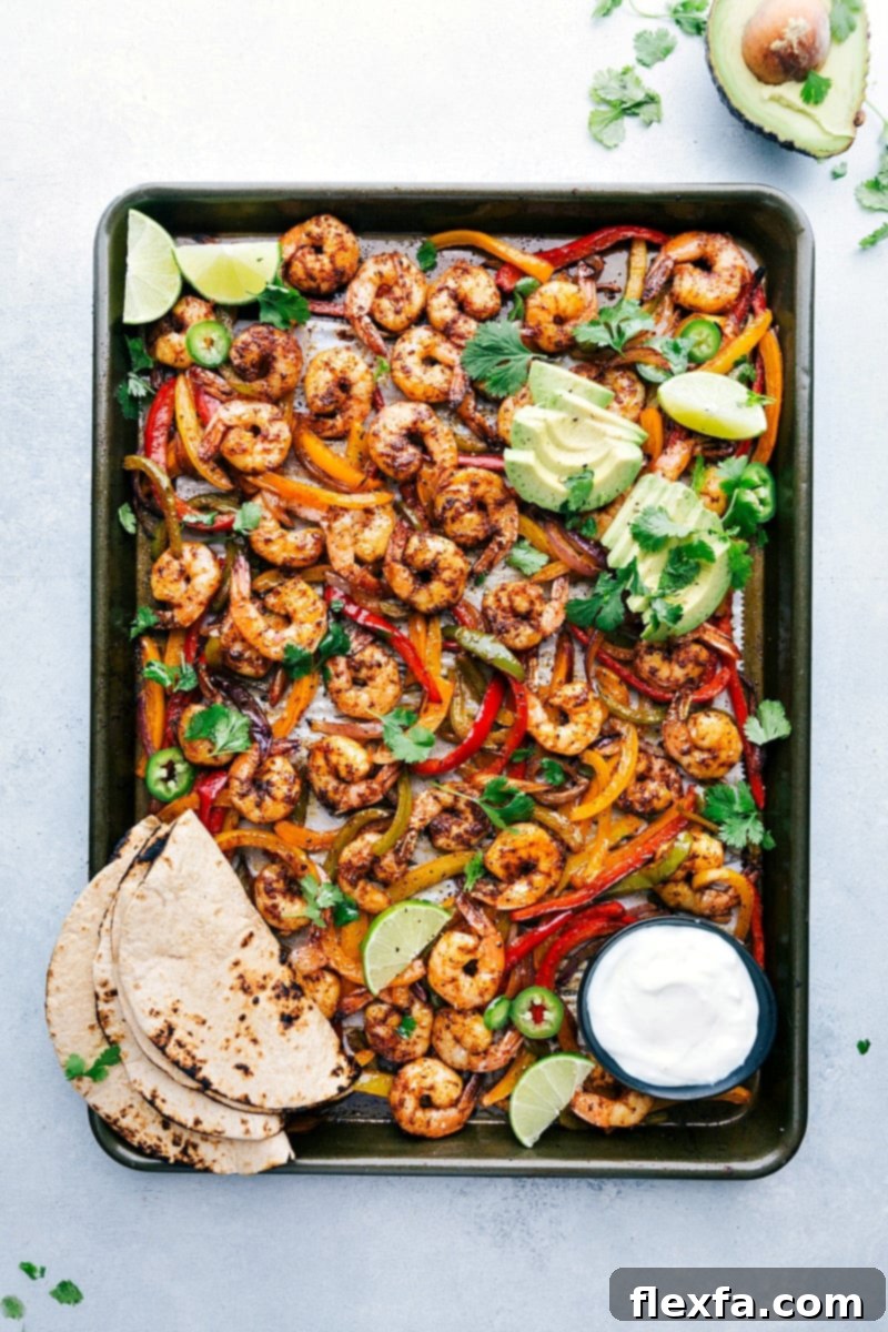 Freshly baked sheet pan shrimp fajitas, vibrant with colorful peppers and onions, served with warm tortillas and a selection of toppings for assembly.