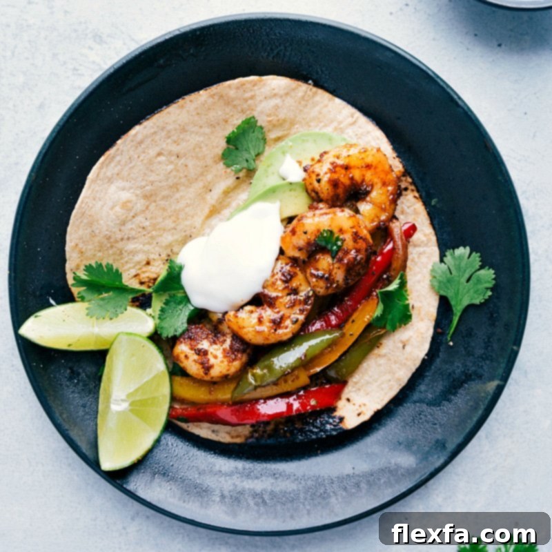 A perfectly assembled shrimp fajita, nestled in a warm tortilla, garnished with fresh cilantro, a dollop of sour cream, and a bright lime wedge.